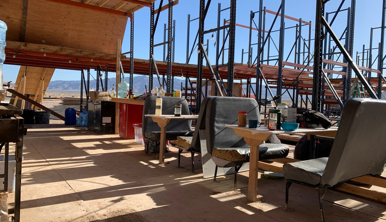 The common area of Freeside with tables and chairs inside a pallet-rack structure.